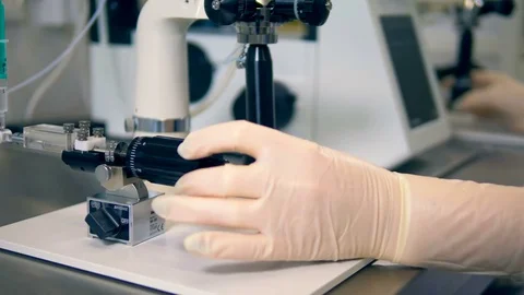 Gloved technician hands turn microscope knobs. Stock Footage 84634692