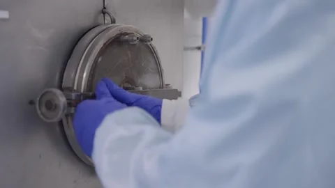 Gloved technician in sterile cleanroom operating a stainless steel vacuum Video stock 325869006