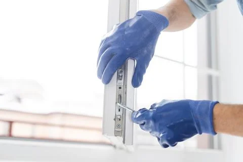 A gloved worker adjusts the installed plastic door Stock Photos