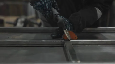 Gloved worker guides handheld cutting tool across steel in workshop, producing Vídeo Stock 347017064