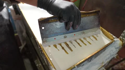Gloved worker pulling a metal squeegee across a bed of white chalk slurry to Stock Footage 342897279