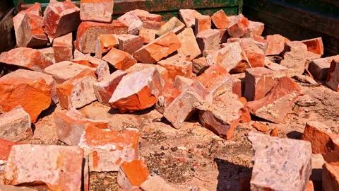 Gloved worker sorting red clay bricks at demolition site in bright daylight Stock Footage 321785072