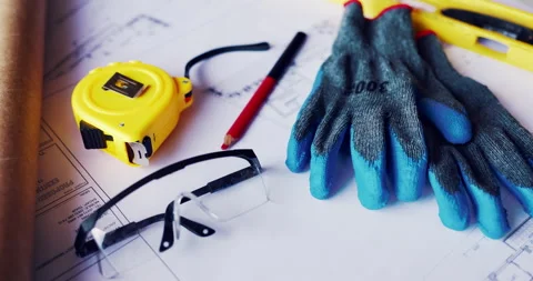 Gloves, architecture and blueprint on table with safety documents, construction Stock Footage 336780409