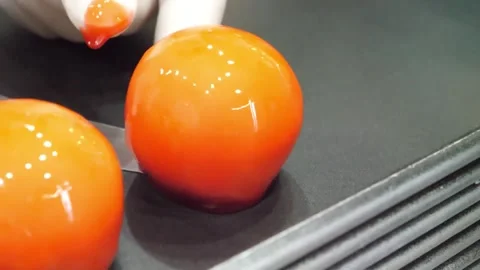 Gloves dipping smooth spherical orange pastries in glaze close up Video stock 345292051