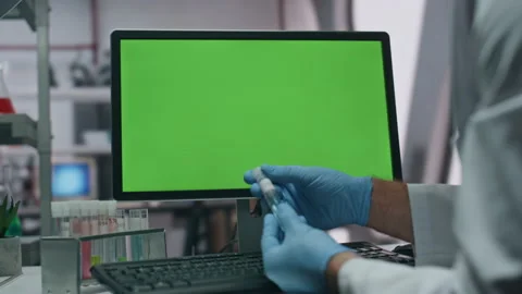 Gloves hands taking test tube entering research data in green screen computer Stock Footage 254619361