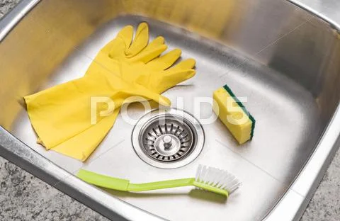 Gloves, sponge and brush in a clean kitchen sink Stock Photos