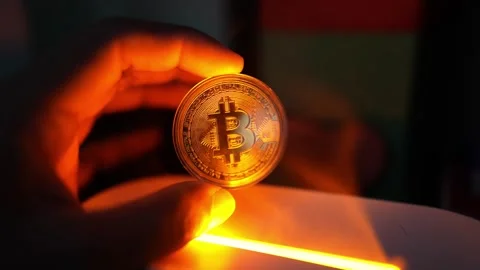 Glowing Bitcoin Coin in Hand with Orange Light, A hand holding a glowing Bi.. Stock Footage 304875417