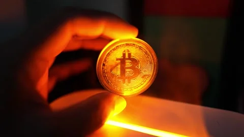 Glowing Bitcoin Coin in Hand with Orange Light, A hand holding a glowing Bi.. Vídeo Stock 304875462