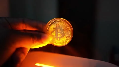 Glowing Bitcoin Coin in Hand with Orange Light, A hand holding a glowing Bi.. 库存影片 304875499