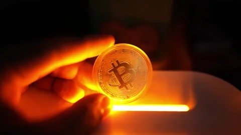 Glowing Bitcoin Coin in Hand with Orange Light, A hand holding a glowing Bi.. 動画素材 304876876