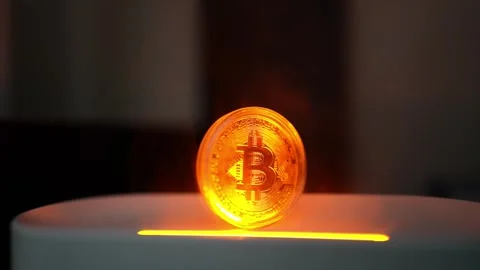Glowing Bitcoin Coin on Smooth Surface, A glowing Bitcoin coin standing upr.. Stockbeeldmateriaal 304876354