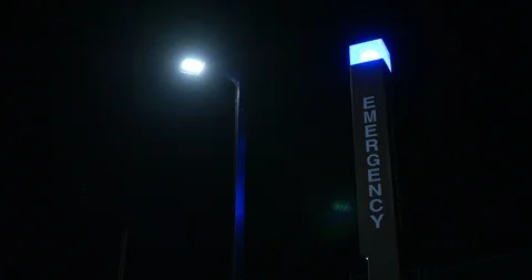 Glowing blue emergency pole light next to a street light at dark. Stock Footage 114758450
