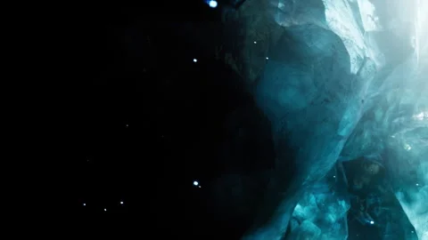 Glowing blue ice cave with light from above in a dark setting Stock Footage 344549449