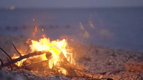 Glowing bonfire on the beach at sunset. Beautiful fire by the sea Stock Footage 157724940