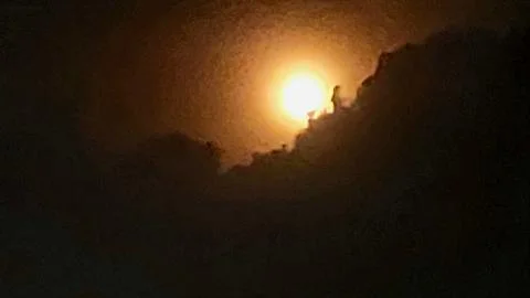 Glowing Bright Full Moon Shining Behind Dark Clouds At Night Foto stock