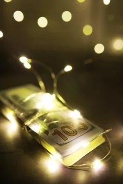 Glowing Bundle of 100 Dollar Bills Wrapped in String Lights Stock Photos