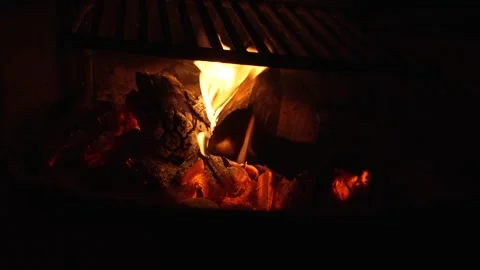 Glowing campfire embers and flames under a grill grate at night Stock Footage 346794744