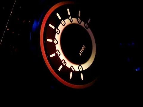 Glowing car tachometer dashboard dial in dark night interior. Stock Photos
