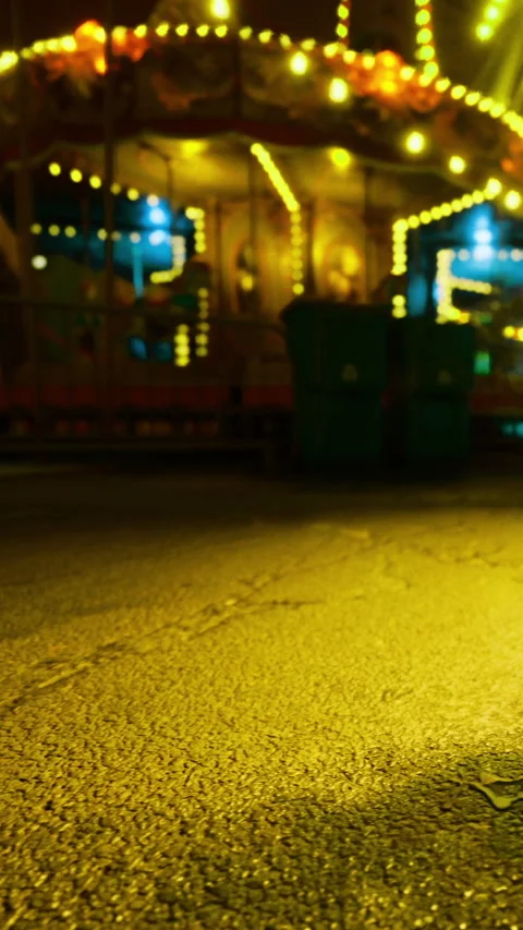 Glowing carousel lights illuminate a deserted street at night Stock Footage 340077359