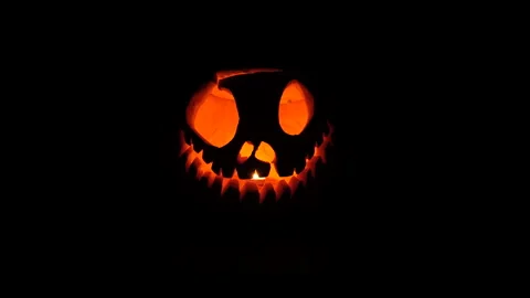 Glowing Carved Jack-o'-Lantern with Candle Flame on Black Background Stock Footage 342562932