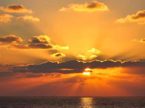 Glowing Clouds and Sun Rays over the Sea at Dusk Stock Photos