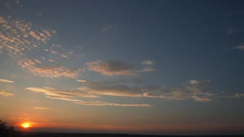 Glowing clouds move across a colorful sunset sky in time lapse, dramatic Stock Footage 346195547