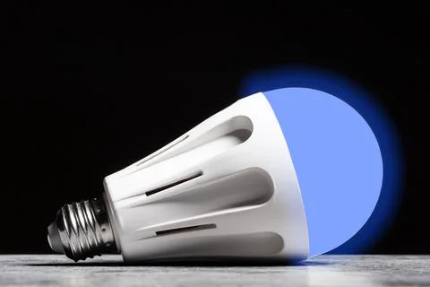 Glowing cold light LED bulb on the grey table on black background Stock Photos