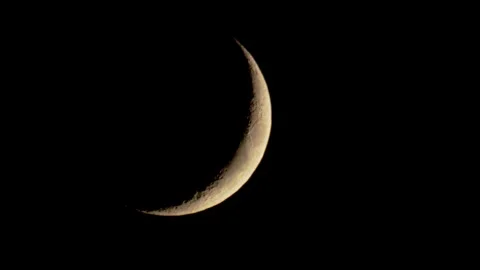 A glowing crescent moon shines in the dark sky Stock Footage 329657154