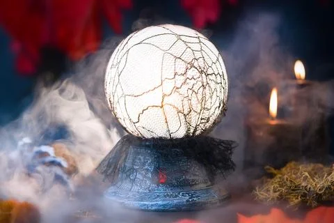 A glowing divination ball on a witch's table, shrouded in puffs of smoke. Stock Photos
