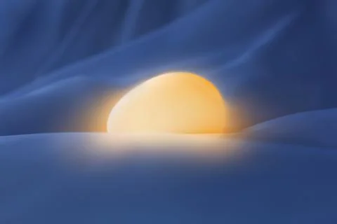 Glowing Easter egg in the blueish silky sheets Stock Photos