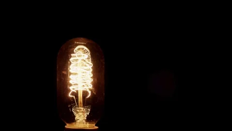 Glowing Edison light bulb flickers on and off dark Stock Footage 329667711
