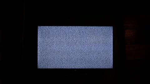 Glowing flat screen television displaying static white noise in pitch-dark room Stock Footage 340526390