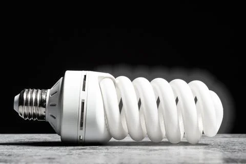 Glowing fluorescent bulb light on the grey table on black background Stock Photos