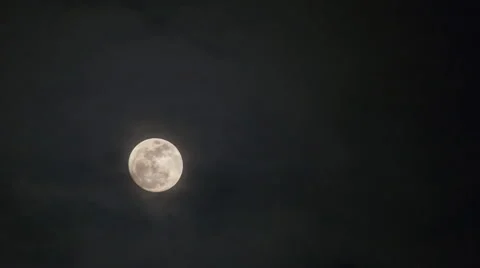 Glowing full moon rising through dark night sky and clouds Stock Footage 49970673