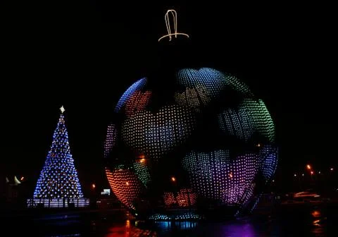 A glowing giant ball with a pattern in the form of hearts and a Christmas fir 写真素材