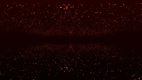 Glowing golden particles fly chaotically on a dark brown background. In the Stock Footage 171080103