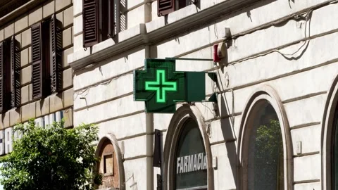 Glowing green cross mounted on a wall signals pharmacy in Rome Stock Footage 306320451