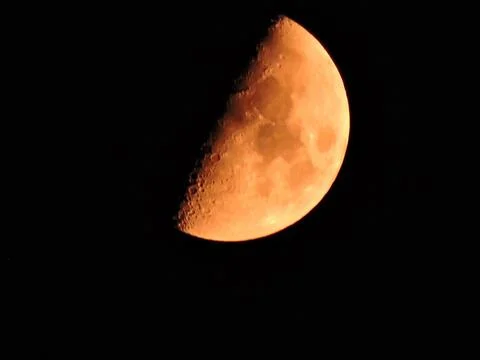 Glowing, half-illuminated crescent or first-quarter moon with a striking ora Stock Photos