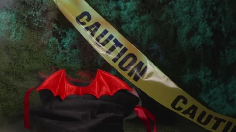 Glowing Halloween bat candy bag behind yellow caution tape in fog Stock-Footage 342520488