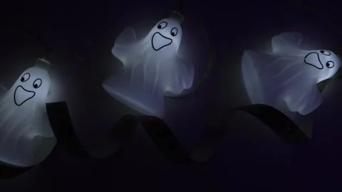 Glowing Halloween ghost decorations placed on a table in a dark room,4K Stock Footage 320642968