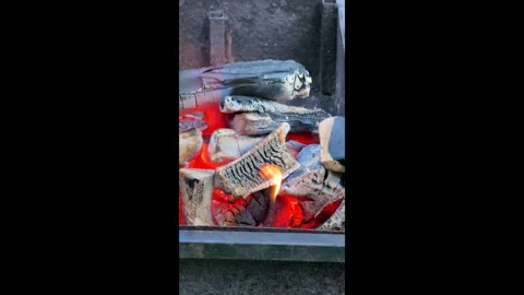 Glowing hot coals burn intensely in a barbecue grill outdoors on a summer day. T Stock-Footage 310845972