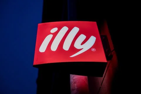 Glowing Illy logo on a wall in night time Stock Photos