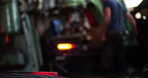 Glowing iron with blacksmith working in background Stock Footage 61353811