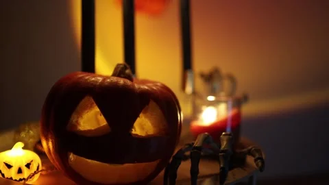 Glowing jack o lantern and skeleton hand create spooky Halloween home decor Stock Footage 346147282
