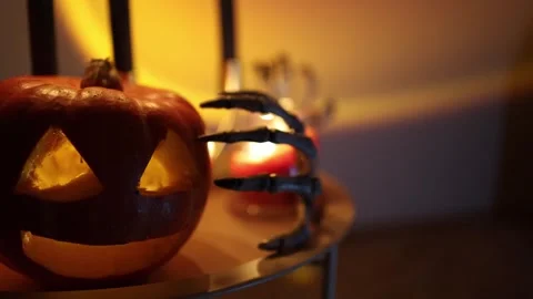 Glowing jack o lantern and skeleton hand create eerie Halloween decoration Stock Footage 346147598