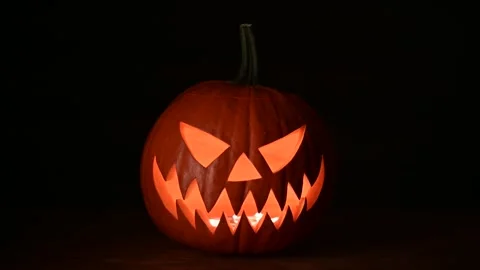 Glowing jack-o-lantern lit from inside on wooden table Stock Footage 317306607