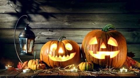 Glowing jack o lanterns with candlelight on a rustic wooden table Stock-Footage 334104806