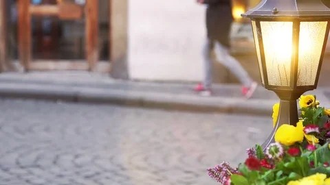 Glowing lantern and flower bed against tourists Stock Footage 74767131