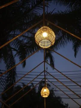 A glowing lantern hanging under palms at dusk, Thailand Stock Photos