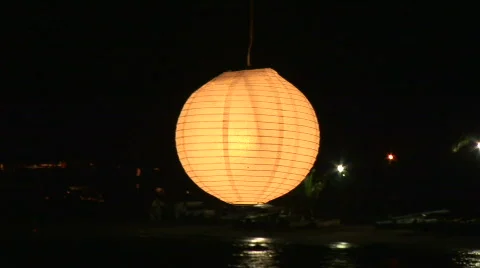 A glowing lantern at night with shore in the background Stock Footage 574337